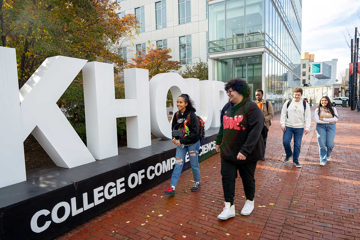 Khoury college sign at northeastern University with students walking by